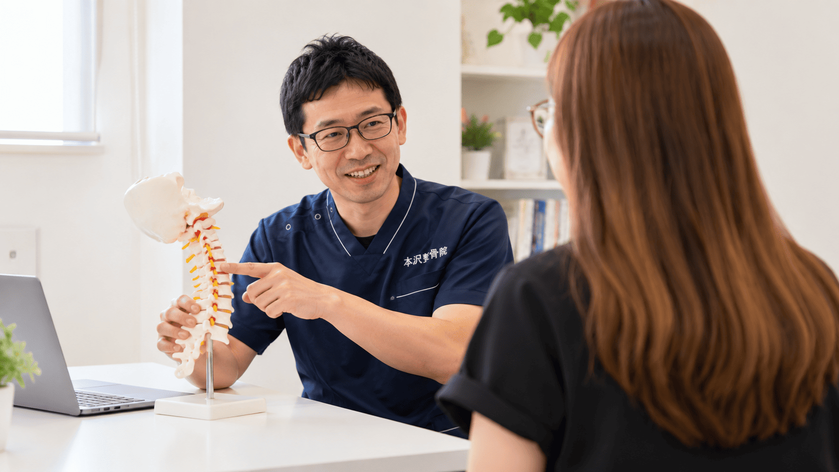 本沢整骨院の柔道整復師が首の骨の模型を使って説明する様子